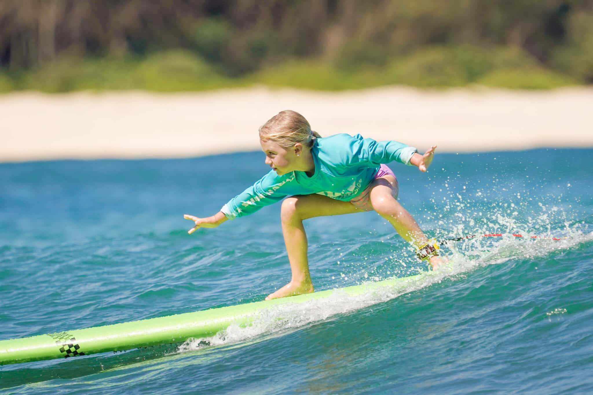 a young girl riding a wave on a surfboard in the water