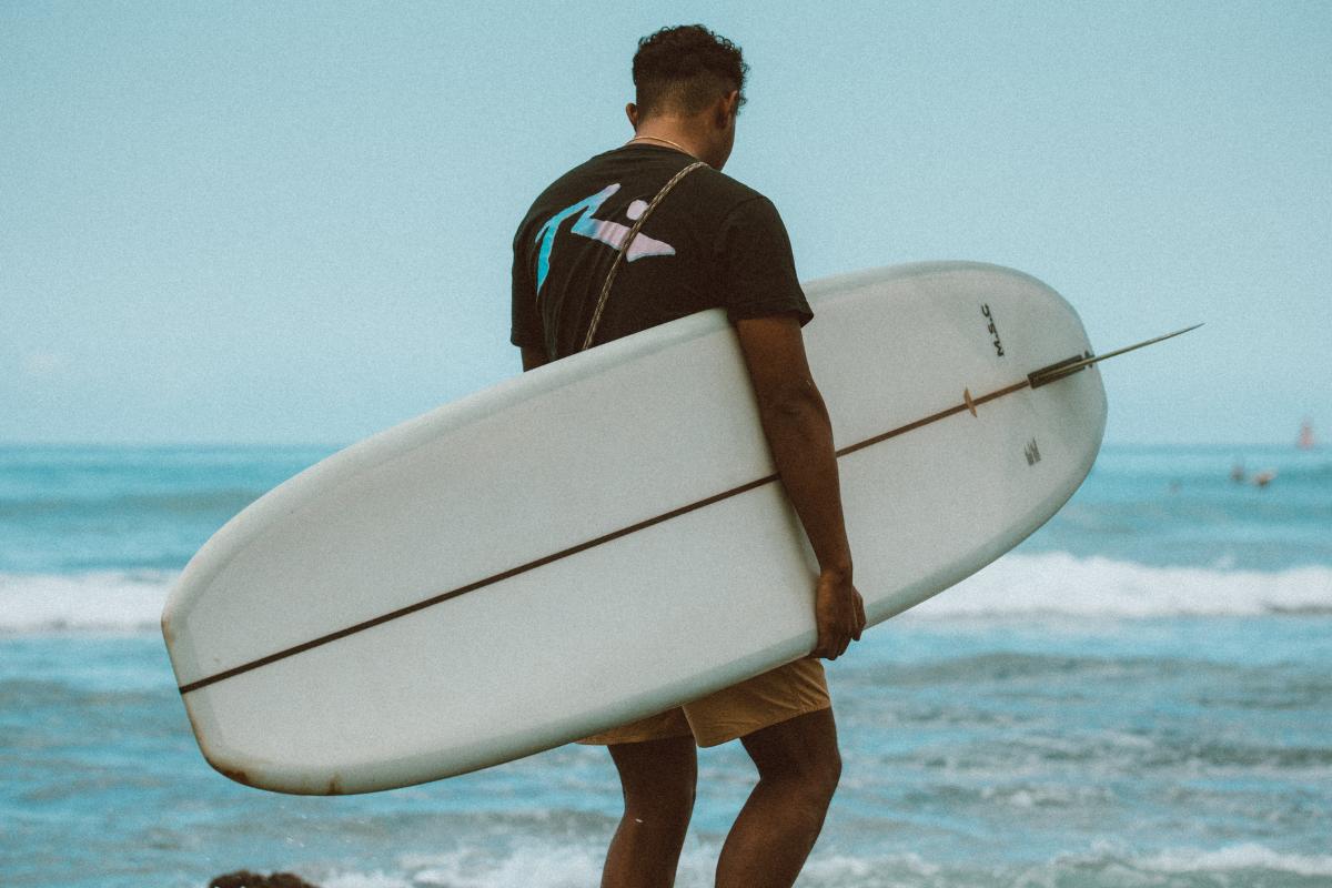 a man carrying a surf board on a body of water